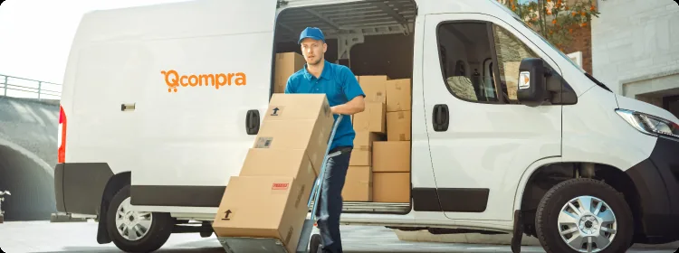 Entregador da Qcompra carregando caixas até uma van com a marca Qcompra